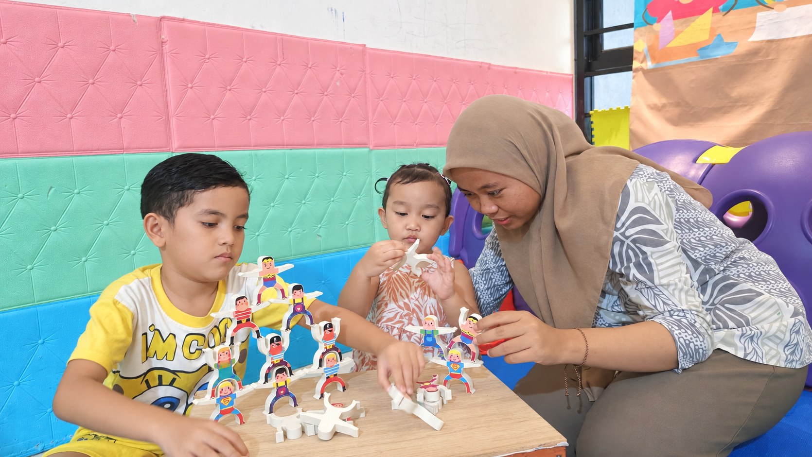 Pengasuh mendampingi anak menyusun mainan