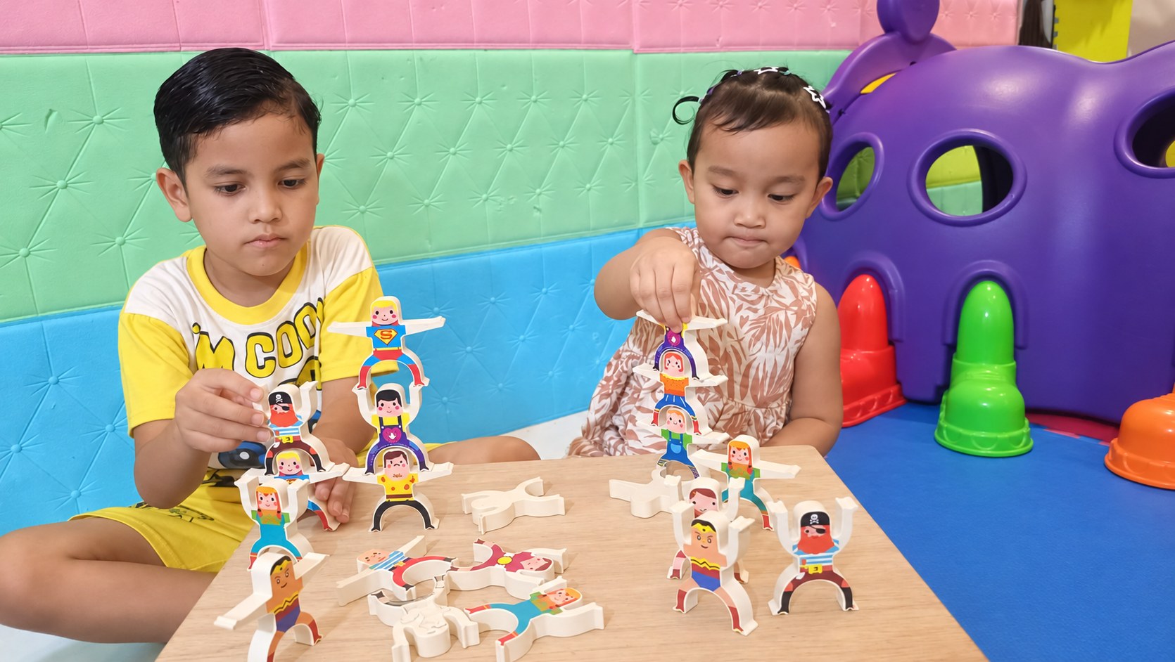 Dua anak berkonsentrasi menyusun mainan keseimbangan
