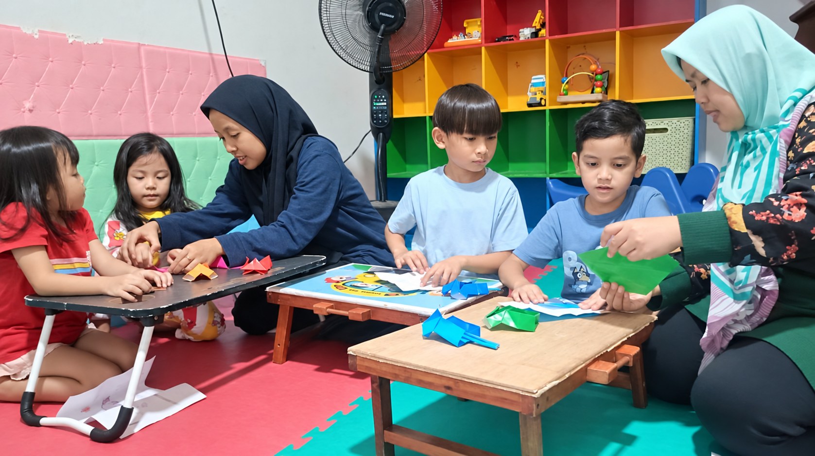 Anak-anak belajar melipat kertas bersama pengasuh Okaeri