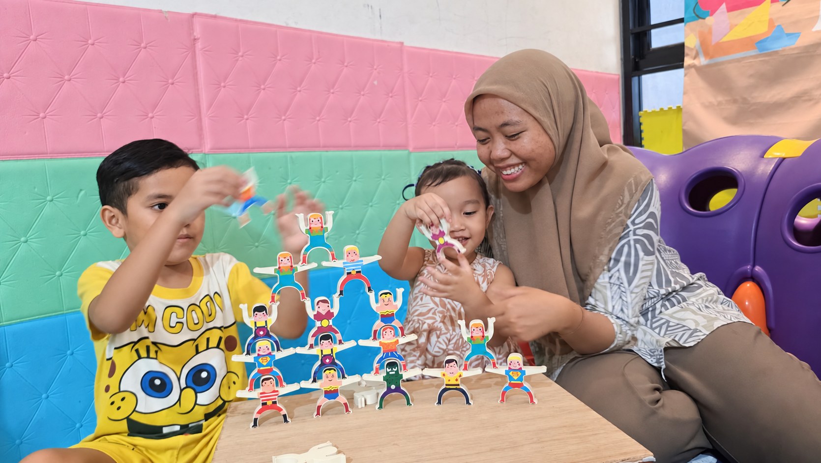 Pengasuh Okaeri tersenyum mendampingi anak-anak bermain susun balok